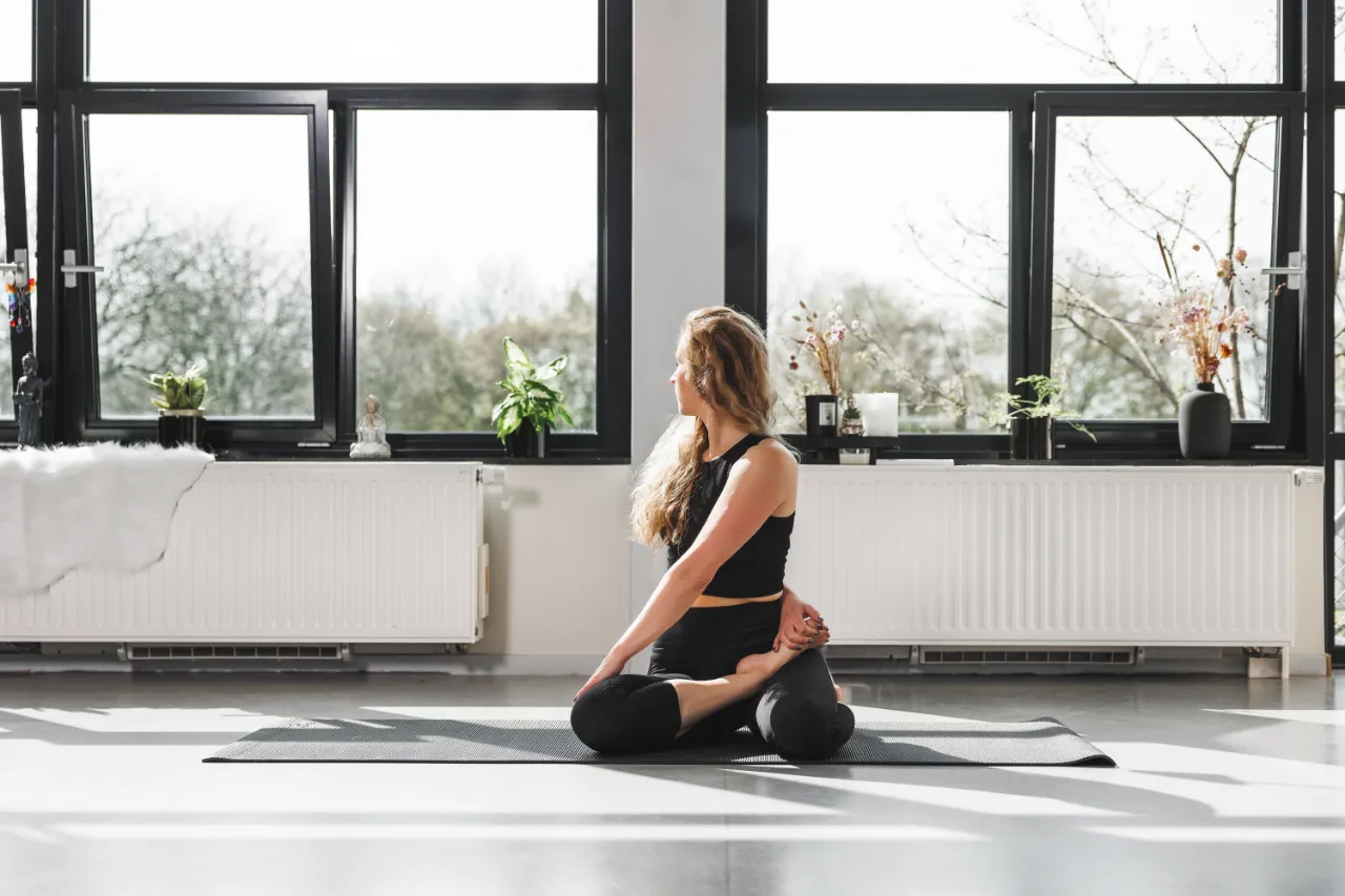 Vrouw beoefent yoga bij het raam