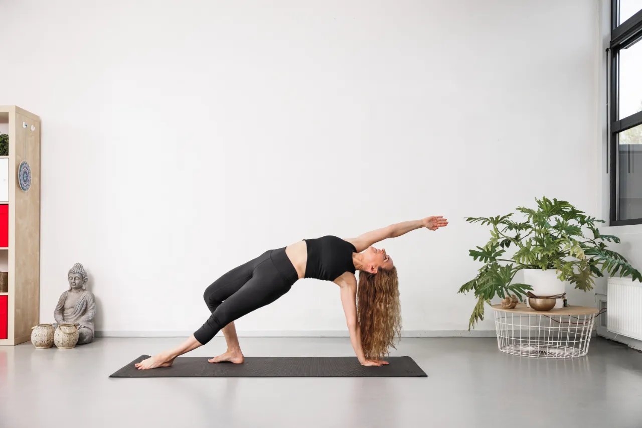 Vrouw in een zijwaartse yogahouding op de mat
