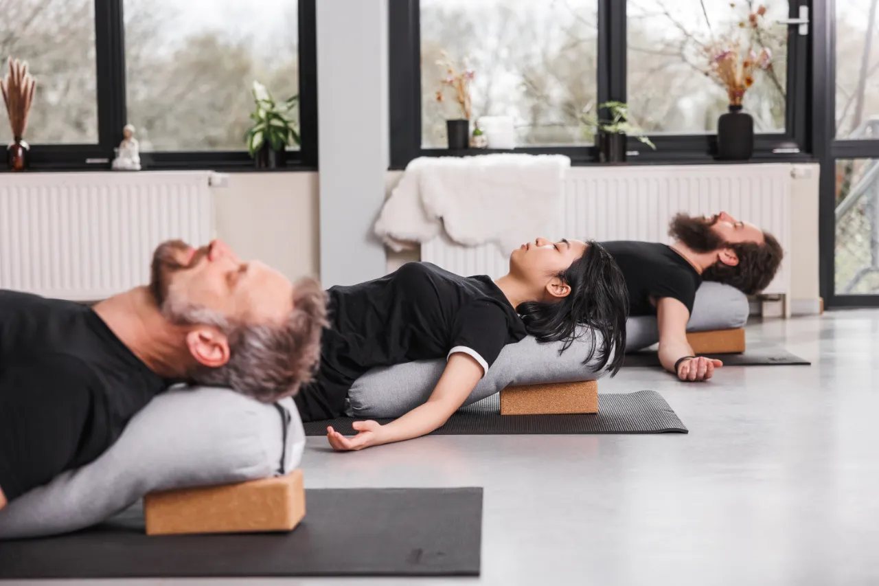 Deelnemers ontspannen liggend op yogablokken